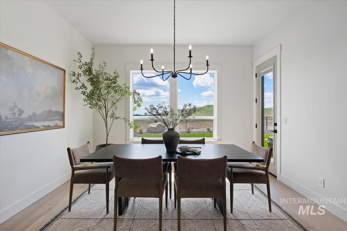 7615 Brown Way Eagle, ID 83714 - Photo 22 of 43 Dining area with light wood-finish flooring, a contemporary black chandelier, and a large window offering expansive views of distant hills
