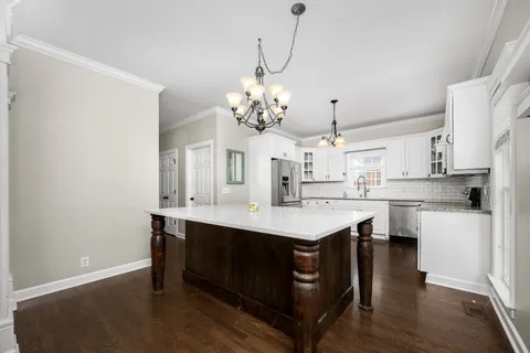 a kitchen with kitchen island granite countertop a sink a island with wooden floor and cabinets