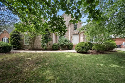 a view of a house with backyard garden and trees
