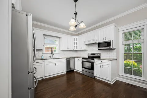 a kitchen with stainless steel appliances white cabinets a sink a stove a refrigerator and microwave