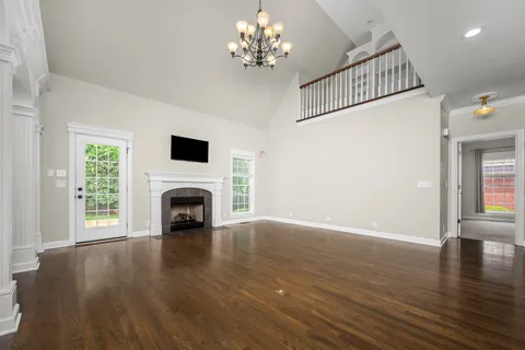 a view of an empty room with wooden floor fireplace and a window
