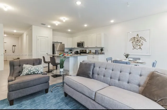 a living room with furniture kitchen view and a chandelier