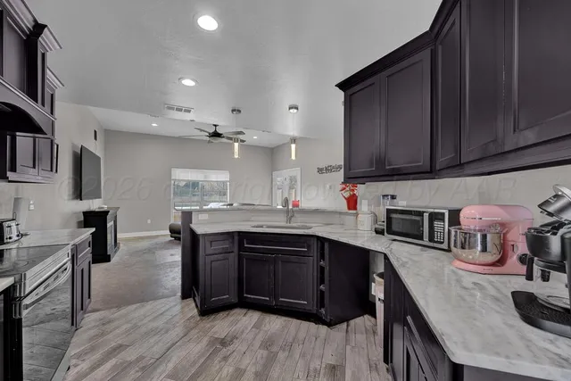 a kitchen with stainless steel appliances granite countertop a sink dishwasher stove and wooden cabinets with wooden floor