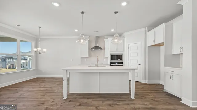 a kitchen with stainless steel appliances granite countertop a refrigerator a stove a microwave and white cabinets with wooden floor