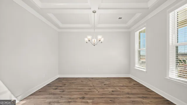 an empty room with wooden floor chandelier and windows