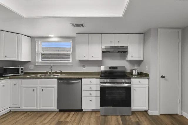 a kitchen with granite countertop white cabinets and stainless steel appliances