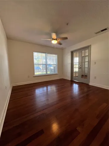 a view of an empty room with wooden floor and a window
