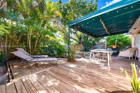 a view of patio with table and chairs under an umbrella with a barbeque