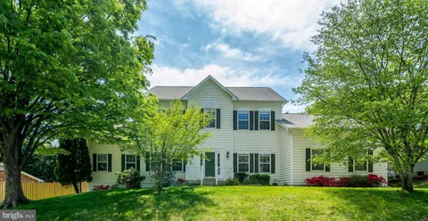 a kitchen with stainless steel appliances granite countertop a stove a sink dishwasher a refrigerator and white cabinets with wooden floor