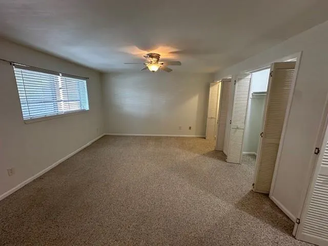an empty room with windows and fan