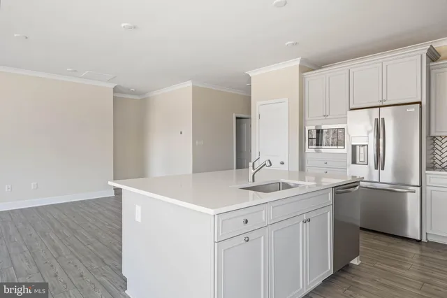 a kitchen with a sink a stove a refrigerator and white cabinets