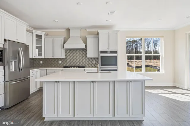 a kitchen with kitchen island a counter top space a sink stainless steel appliances and cabinets