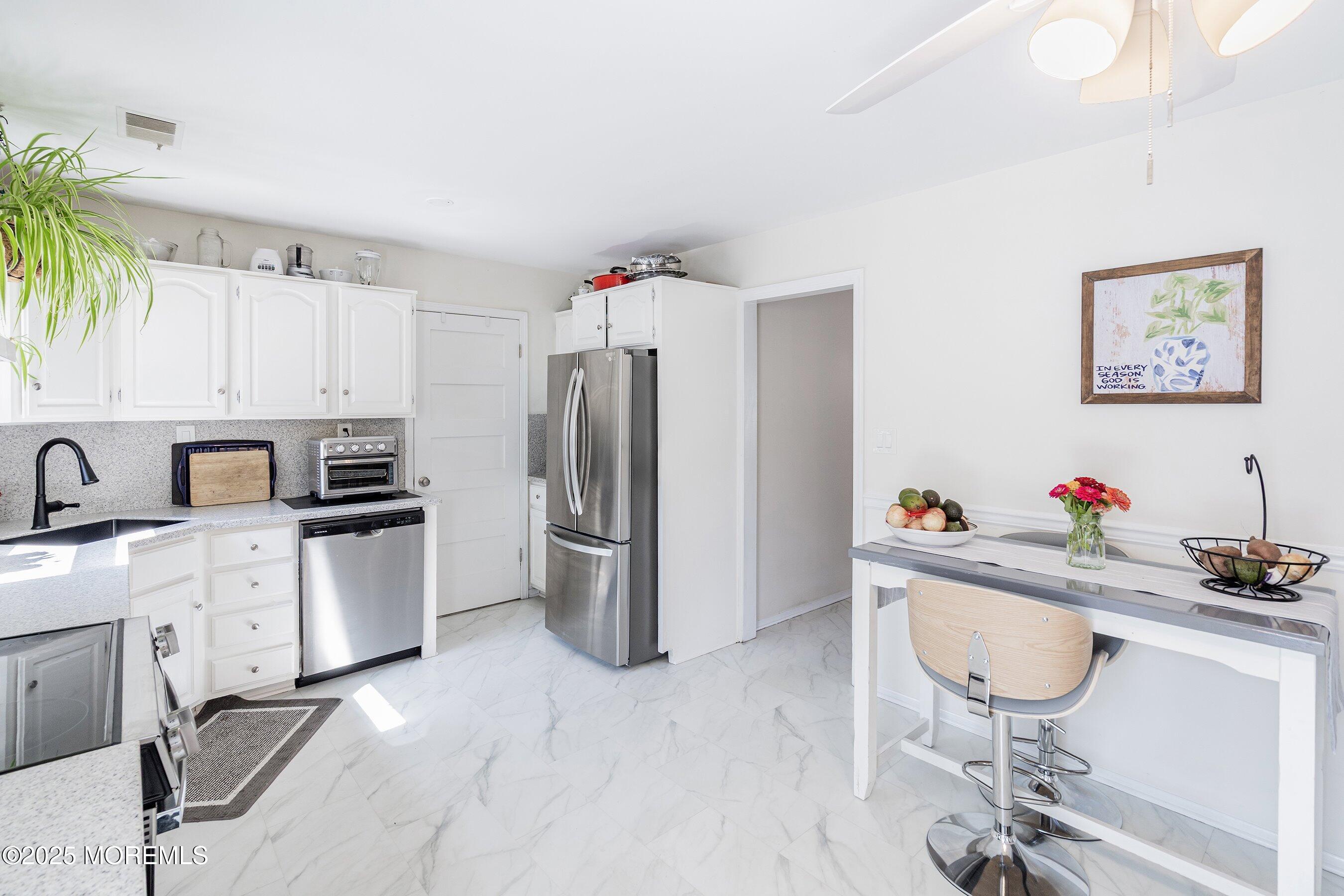 718 Millbrook Road Brick, NJ 08724 - Photo 6 of 26 a kitchen with stainless steel appliances a sink a stove a refrigerator cabinets and dining table