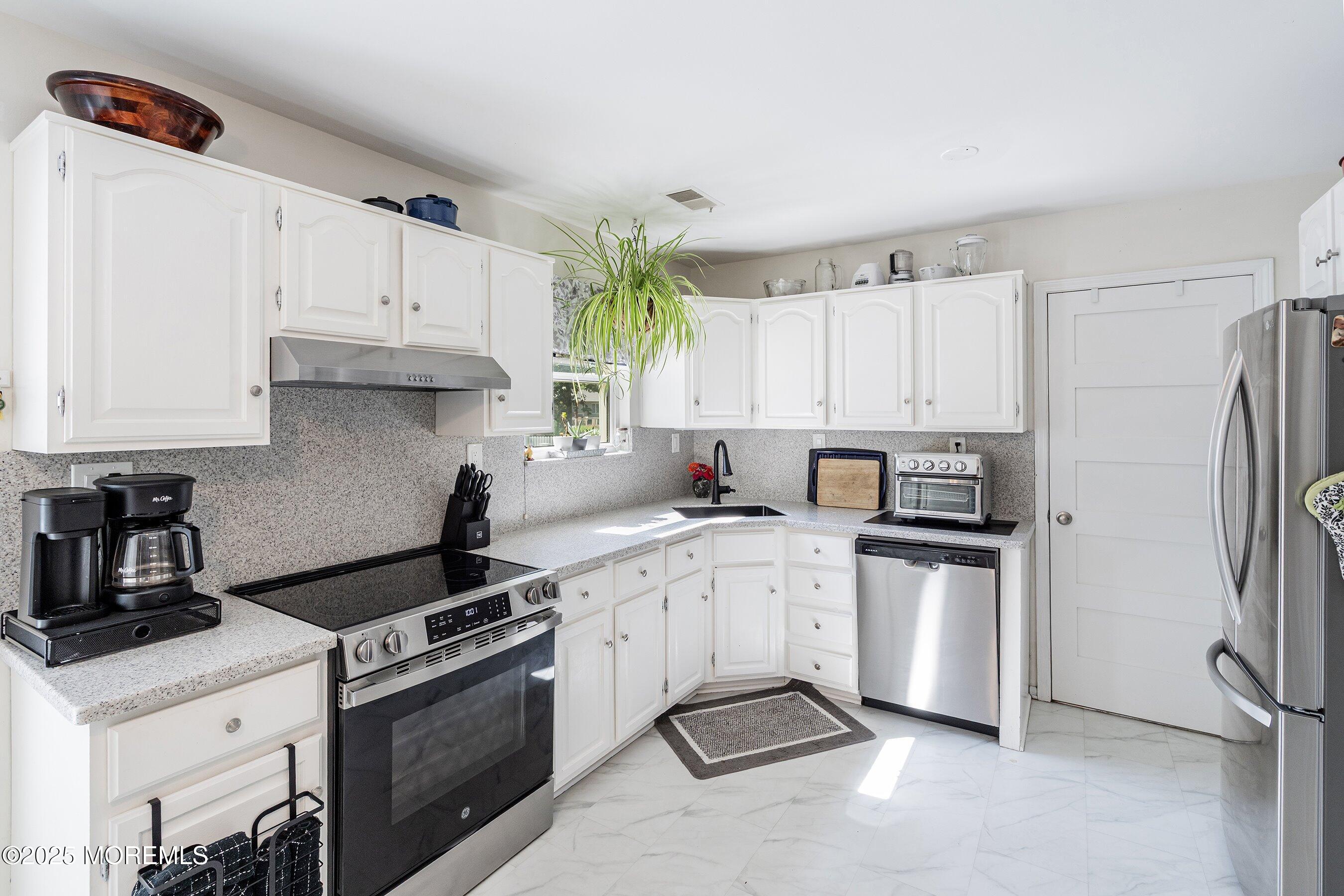 718 Millbrook Road Brick, NJ 08724 - Photo 7 of 26 a kitchen with white cabinets and appliances