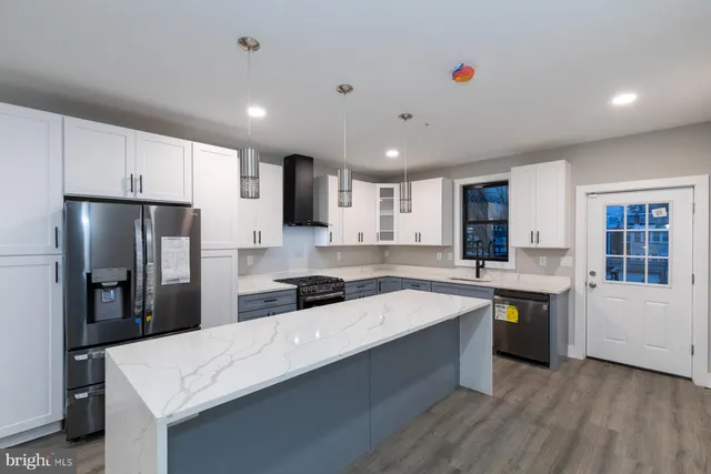 a room with stainless steel appliances kitchen island granite countertop a refrigerator and a stove top oven