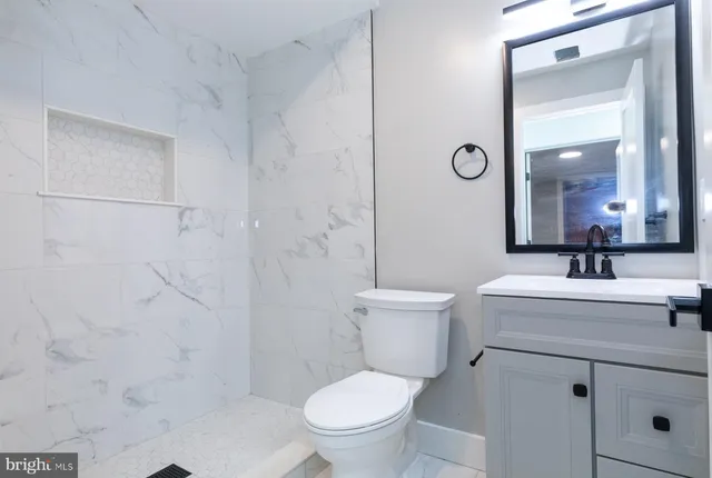 a bathroom with a toilet a sink a mirror and shower