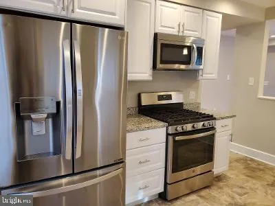 a kitchen with stainless steel appliances white cabinets and a stove top oven