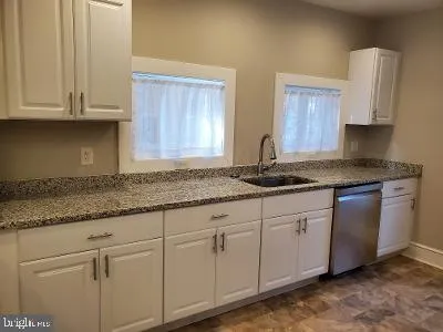 a kitchen with granite countertop white cabinets and sink