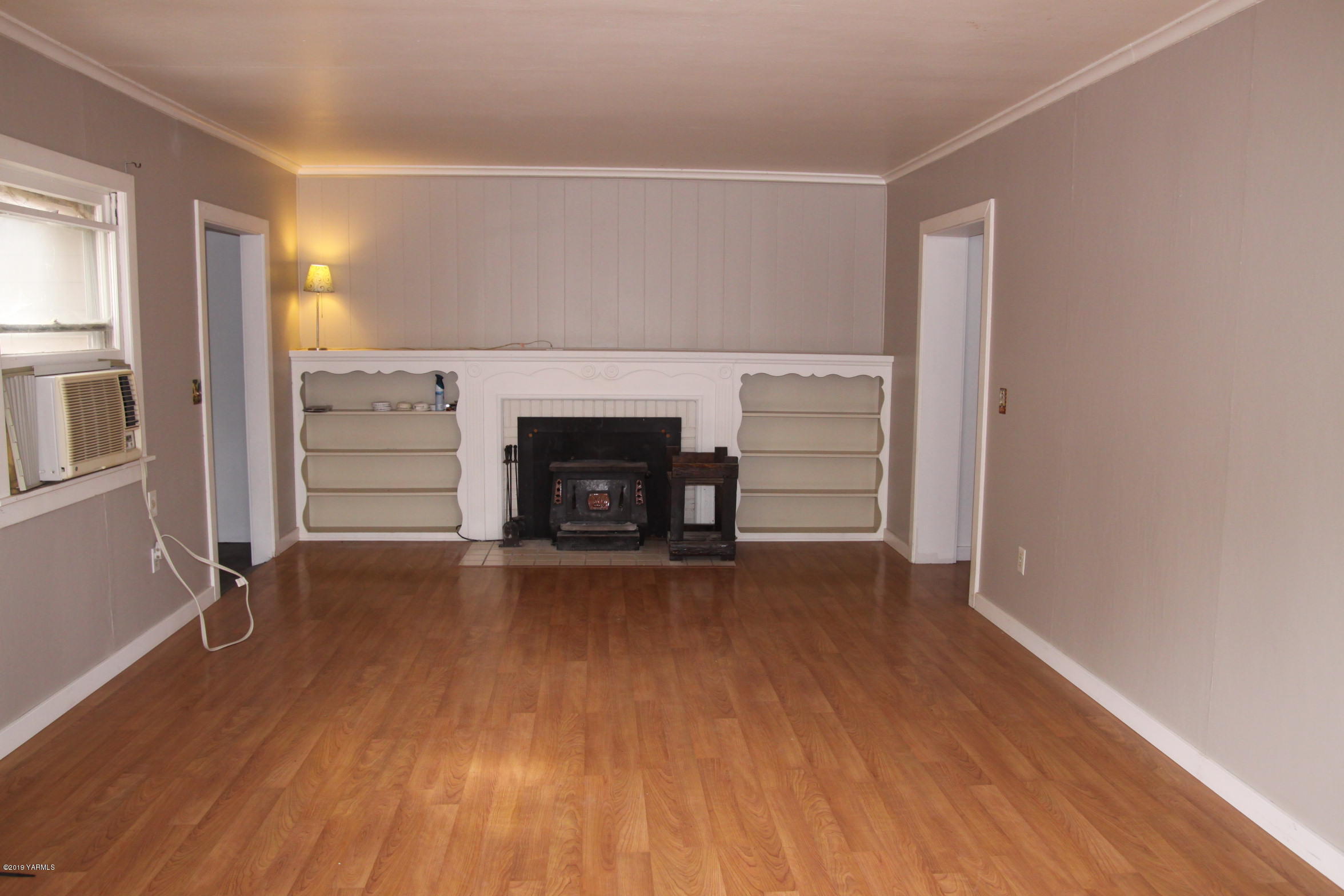 741 McPhee Road Naches, WA 98937 - Photo 3 of 16 an empty room with wooden floor fireplace and windows