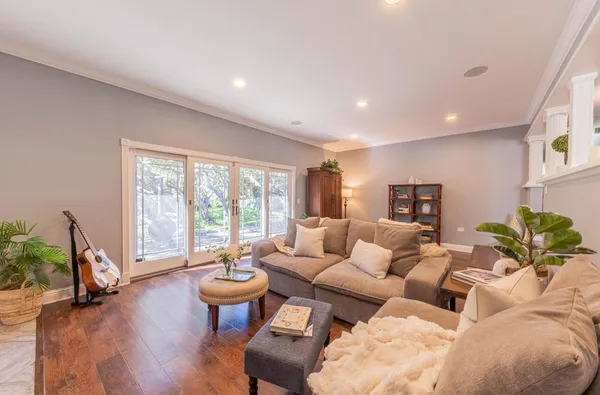 a living room with furniture large windows and wooden floor