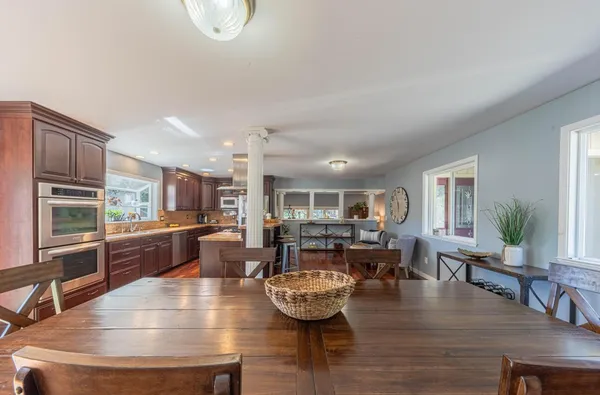 a living room with stainless steel appliances furniture a couch and kitchen view