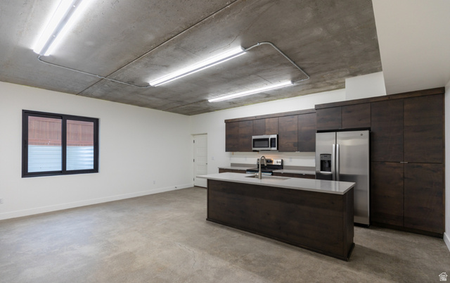 3667 Little Cottonwood Road, Unit 1 Sandy, UT 84092 - Photo 36 of 49 Open-concept living space featuring a contemporary kitchen with dark wood-finish cabinetry, stainless steel appliances, and a central island with a light-toned countertop