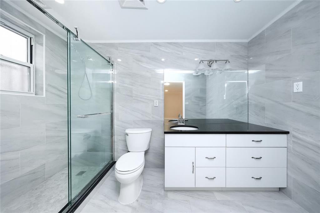 8756 26th Avenue Brooklyn, NY 11214 - Photo 14 of 26 a bathroom with a toilet a sink and glass door