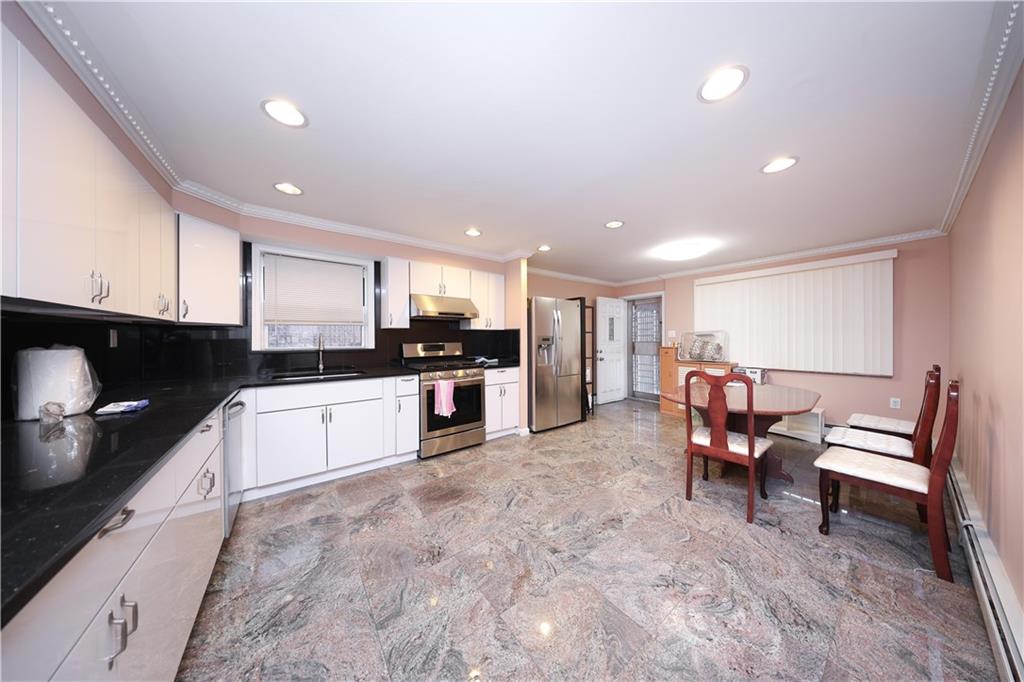 8756 26th Avenue Brooklyn, NY 11214 - Photo 6 of 26 a kitchen with stainless steel appliances kitchen island granite countertop a stove a sink a microwave a dining table and chairs with wooden floor