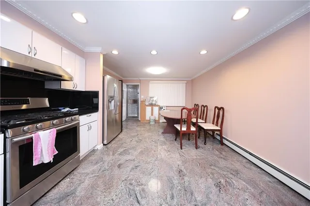 a living room with stainless steel appliances furniture a fireplace and a open kitchen view