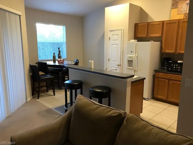 a living room with stainless steel appliances kitchen island granite countertop furniture and a refrigerator