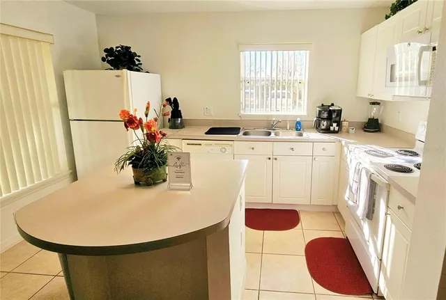 a kitchen with stainless steel appliances granite countertop a sink a refrigerator a stove a dining table and chairs