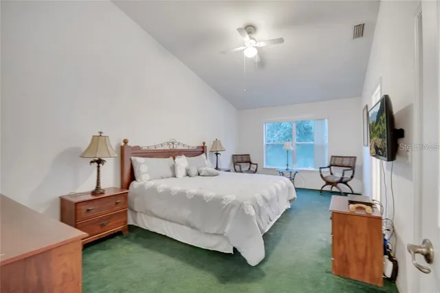 a bedroom with bed a flat tv screen and a dresser