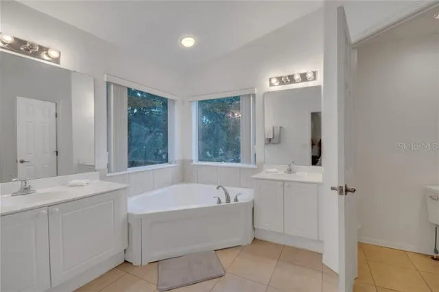 a bathroom with a bathtub a sink a mirror a vanity and window