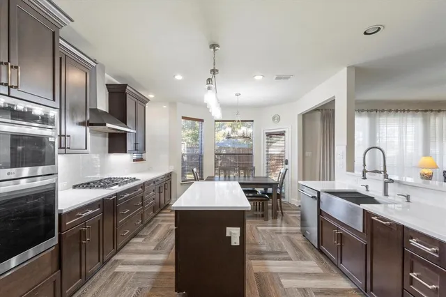 a large kitchen with stainless steel appliances granite countertop a stove top oven a sink dishwasher a dining table and chairs