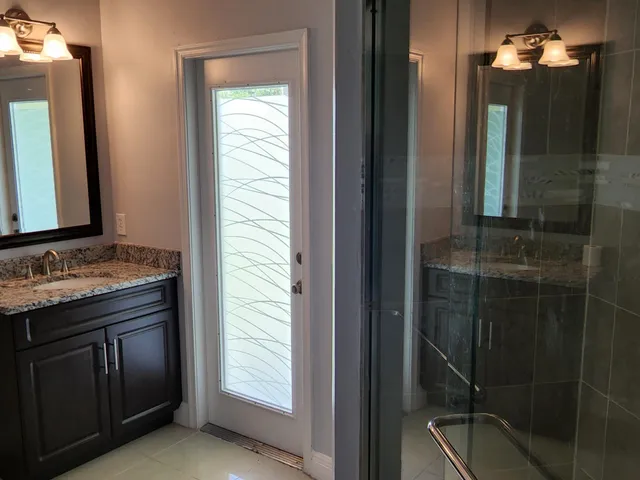 a bathroom with a granite countertop sink a mirror and a shower