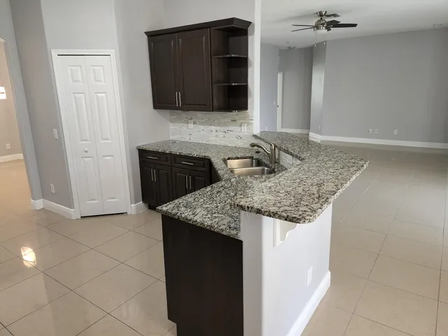 a kitchen with granite countertop a sink and a stove top oven with wooden floor
