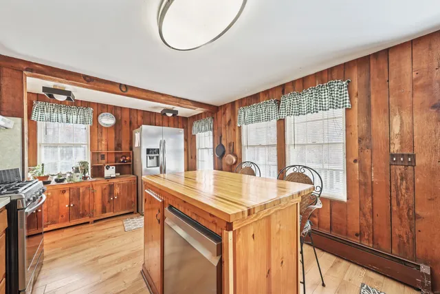 a very nice looking kitchen with granite countertop a stove a sink and a dining table with wooden floor