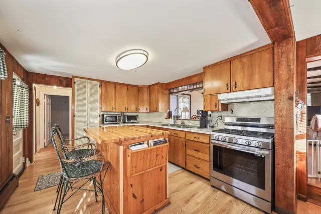 a kitchen with stainless steel appliances granite countertop a stove top oven a sink dishwasher and white cabinets with wooden floor