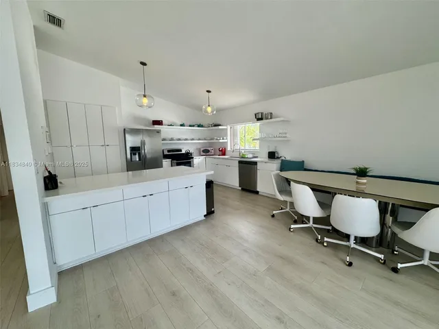 a kitchen with a sink a cabinets and chairs