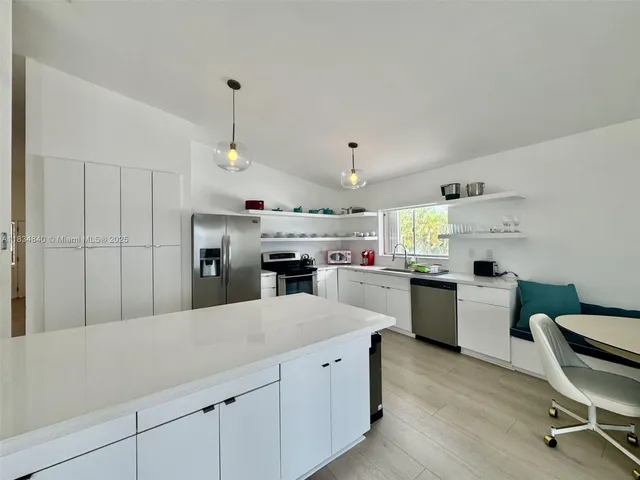 a kitchen with a sink dishwasher a stove and white cabinets with wooden floor