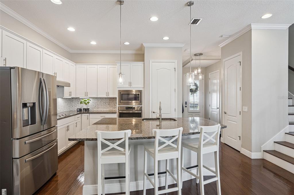 1565 Castile Street Celebration, FL 34747 - Photo 19 of 82 a kitchen with granite countertop a refrigerator and chairs