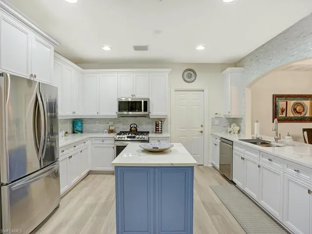 a kitchen with a refrigerator a sink dishwasher and a stove top oven with white cabinets