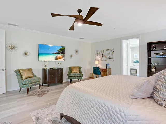 a bedroom with a bed a chair and potted plant on the dresser