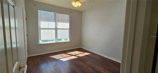 a view of empty room with wooden floor and window