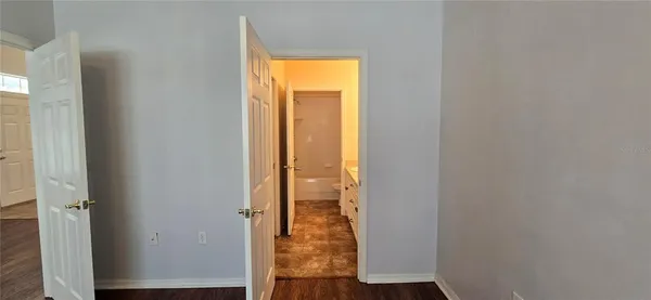 a view of a hallway with wooden floor and a room