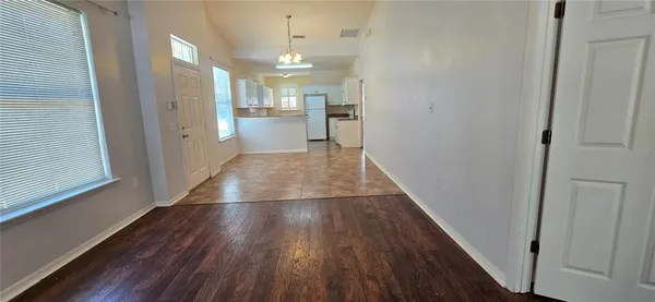 a view of a hallway with wooden floor and a kitchen