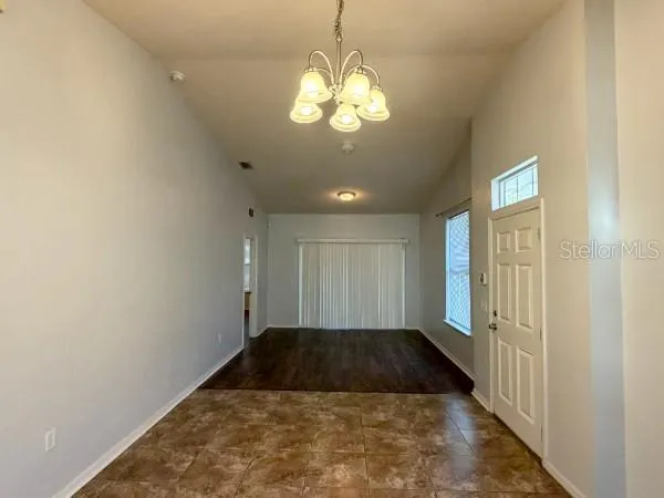 a view of a hallway to a room with a chandelier fan and wooden floor