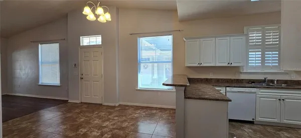 a kitchen with granite countertop a sink window and cabinets