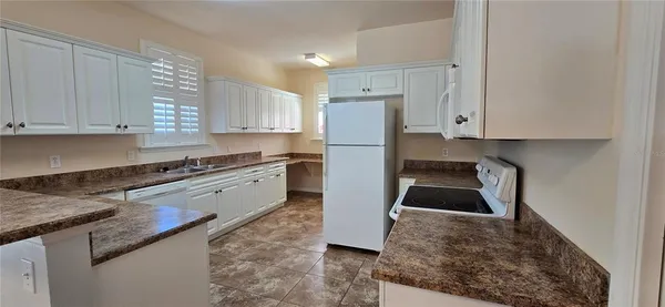 a kitchen with granite countertop a sink a stove and a refrigerator