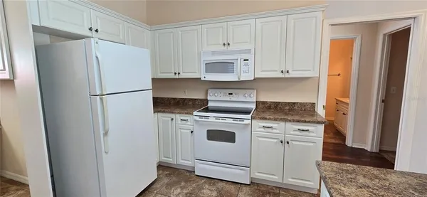 a white refrigerator freezer and a stove sitting inside of a kitchen